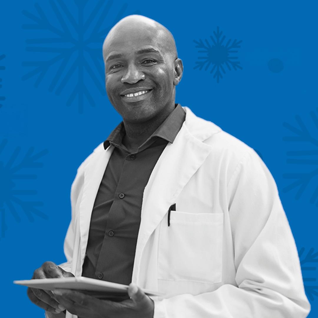 A doctor in back and white ina white lab coat with a clipboard, smiling at the camera. A blue background with snowflake patterns